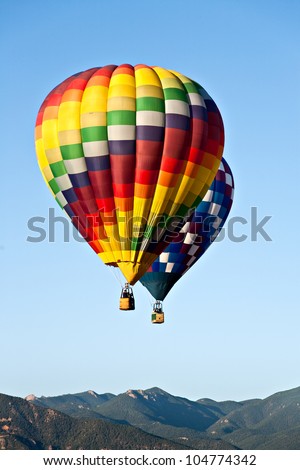 Two hot air balloons ascend over front range mountains during Colorado Springs' 2011 Balloon Classic