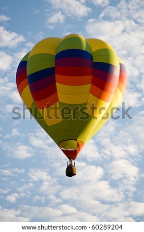 A colorful balloon rises against the beautiful cloudy sky during Colorado Springs Balloon Classic