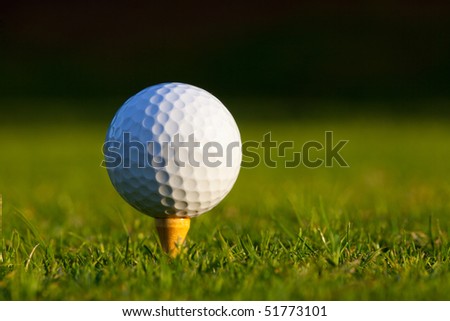 Golf ball on tee on manicured golf course grass