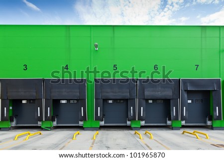 Front view of loading docks in the industrial warehouse with green wall and enumerated black doors