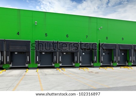 Front view of loading docks in the industrial warehouse with green wall and enumerated black doors