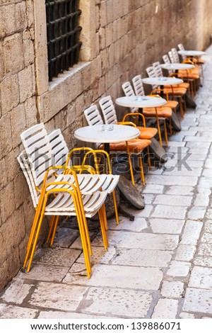 Row of plastic restaurant chairs and tables aligned by the wall before opening of the restaurant in a narrow street in Dubrovnik, Croatia
