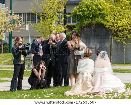 VANCOUVER, CANADA - MAY 12, 2007: Guests and family taking photos of bride and bridesmaid by Lost Lagoon in Vancouver. Lost Lagoon is near entrance to Stanley Park and is a popular wedding venue.