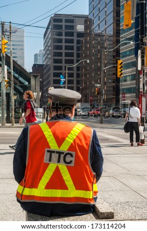 TORONTO, CANADA - MAY 10, 2007: Officer of  Toronto Transit Commission observing traffic at University Ave. and King St. West. TTC is public transport agency that operates bus and streetcar services.