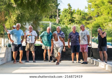 VELI IZ, CROATIA - AUGUST 19, 2014: Group of senior citizens playing game of boules on the playing field. Boules is popular recreational activity of senior citizens in Dalmatia region of Croatia.
