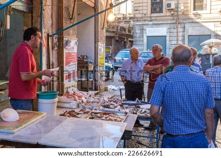 PALERMO, ITALY - OCTOBER 23, 2014: Customers and sellers buying and selling fish and sea products on Vucceria farmer\'s market on streets of old Palermo city center. It is most famous Palermo market.