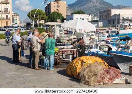 PALERMO, ITALY - OCTOBER 21, 2014: Customers and sellers buying and selling fish and sea products on  farmer\'s market on streets of Palermo city center. It is most famous Palermo market.