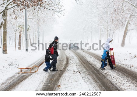 ZAGREB, CROATIA - DECEMBER 28, 2014: Family of four carefully crossing the street covered with snow and mud, during heavy snowstorm, heading for the park to enjoy and play with the kid.