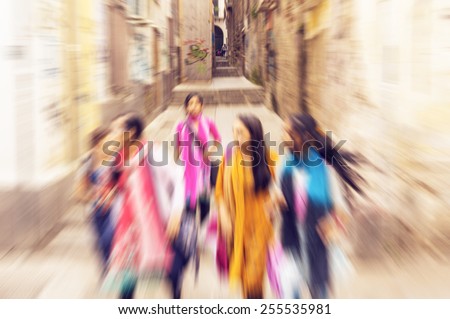 Five multiracial young girls on the streets of Palermo, Italy running in the historic city centre - radial zoom effect defocusing filter applied, with vintage instagram look