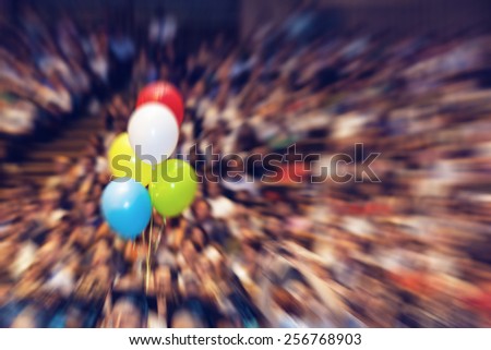 Audience in a big concert hall during graduation ceremony. Balloon set as concept of celebration and graduation ceremony. Radial zoom effect defocusing filter applied, with vintage instagram look.