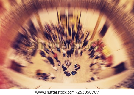 Social gathering of people inside a building, view from above. Radial zoom effect defocusing filter applied, with vintage instagram look.