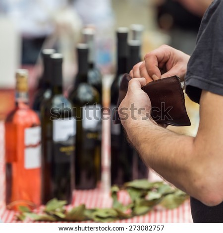 Man reaching for his wallet at the street bar in order to pay for the bottles of wine