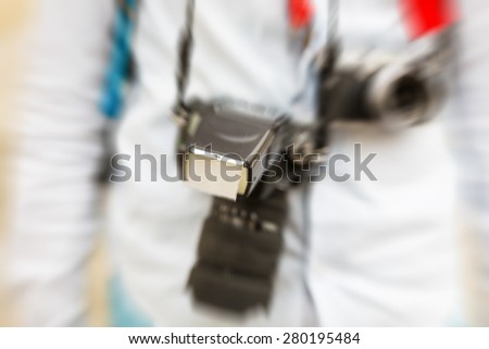 Photographic equipment hanging on straps from the stylishly dressed photographer\'s neck, radial zoom defocusing filter applied