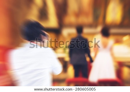 Photographer taking photos of young couple getting married in christian church - religious wedding - radial zoom blur applied, defocused, with instagram filter