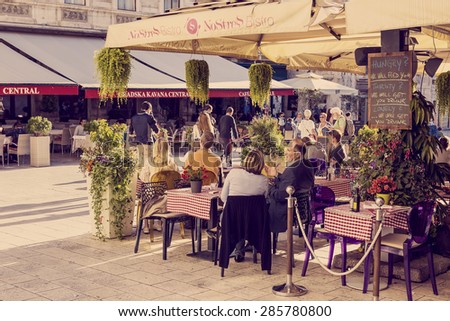 SPLIT, CROATIA - MAY 28, 2015: People in restaurant on main square in Split, Croatia. Split is largest city of Dalmatia and second most largest city in Croatia. Retro look added in postproduction.