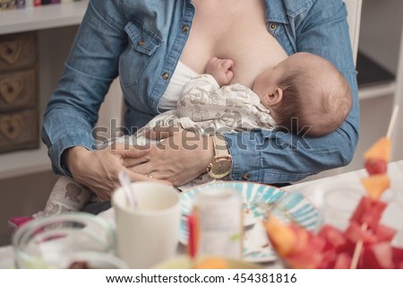 Mother breastfeeding her newborn baby girl during the lunch - breastfeeding on demand - instagram style effect applied