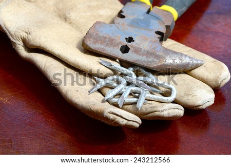 One old working leather glove with hammer and tacks on a table