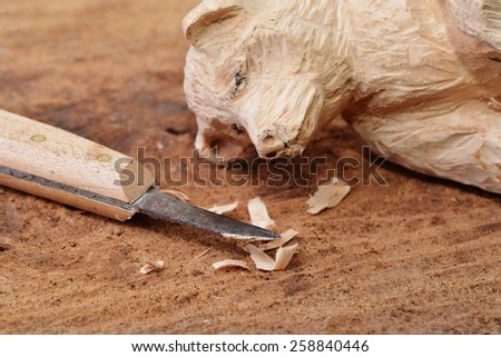 Macro shot of a wood carving knife some wood shavings and a carved figure