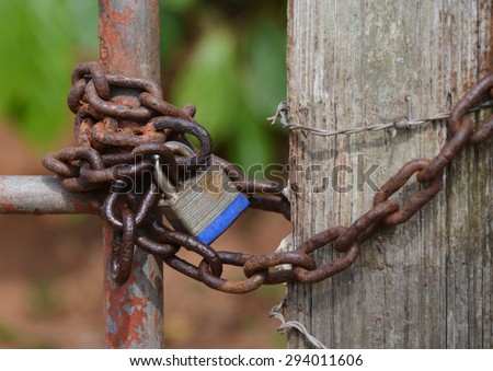 Close up of an old lock and a rusty chain on an iron gate