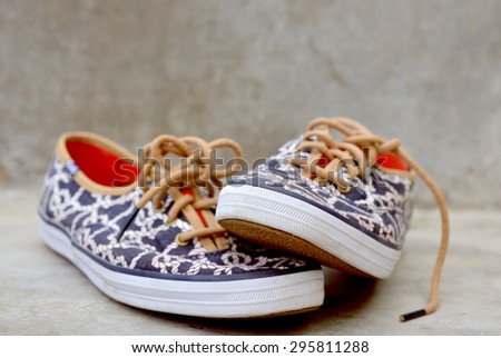 Pair of casual teens tennis shoes on a gray concrete background