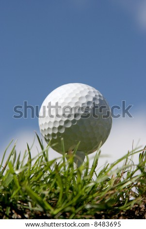 Golf ball on grass against a beautiful blue sky