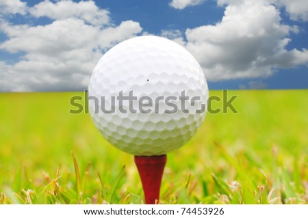 Macro shot of a golf ball against a beautiful blue sky  and green grass