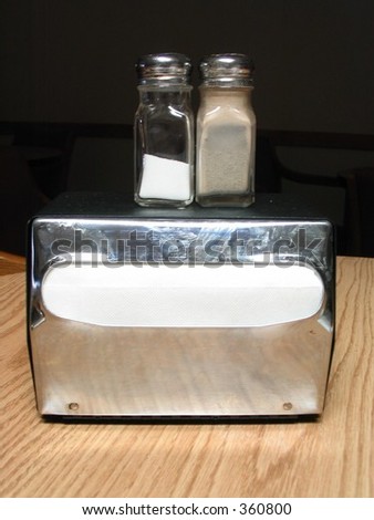 salt and pepper shakers atop a napkin dispenser