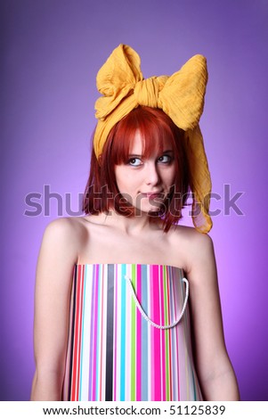 Young girl with yellow bow tie on head in present box at violet background.