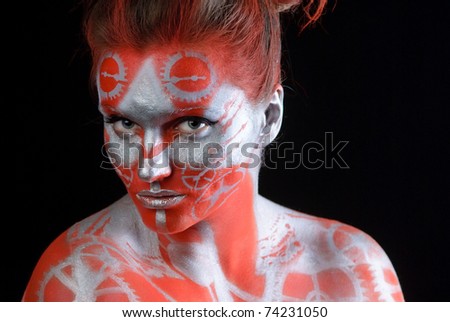 mystic young woman with painted face looking at camera