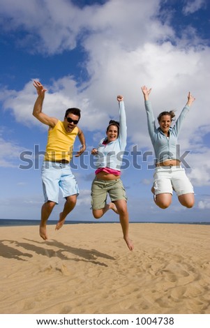 Three young people jumping in a dune.