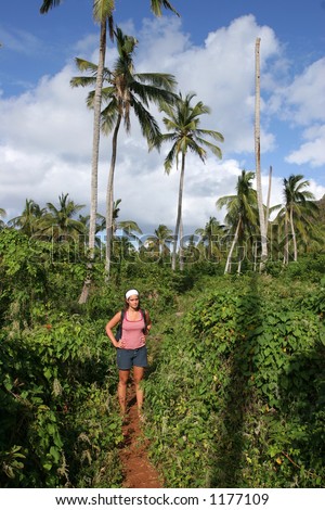 A young woman waking through a tropical jungle.