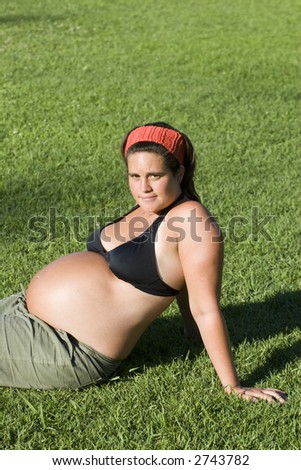 Young pregnant woman laid down on the grass