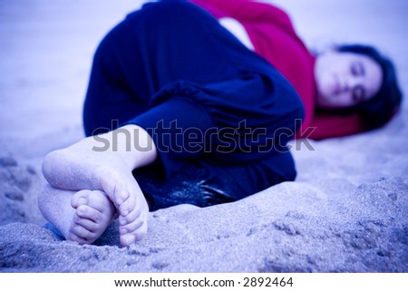 Young woman laid down on the sand