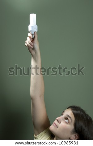 Young woman holding a fluorescent light bulb over a green background