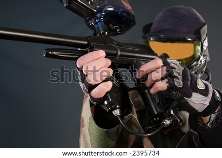 Paintball player with gun, wearing protective mask and cloth