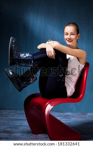 beauty sitting in a red chair on a dark blue background