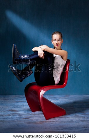 beauty sitting in a red chair on a dark blue background, fright