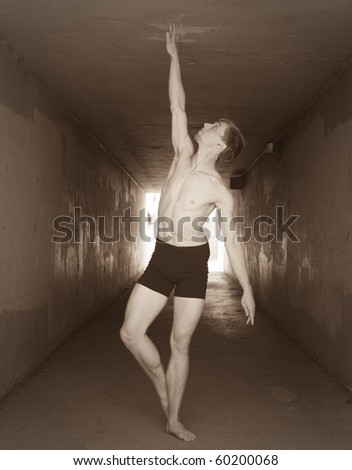 Young man holding ballet pose. Black and white processed with film-like grain.