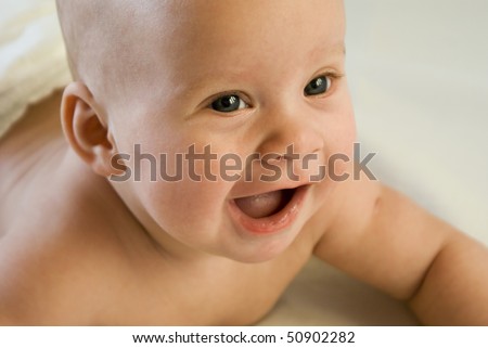 Toothless baby laughs a wide open mouth, wrinkles around the eyes, close-up