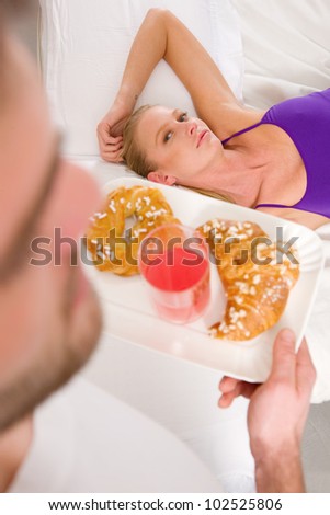 woman lying on the bed man serving breakfast