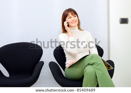 young caucasian woman on the mobile sitting in the waiting room for doctors