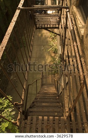 A metal fire escape descending down. An urban city scene of a fire escape and railing looking down.