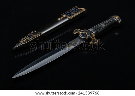 Medieval ceremonial dagger with a jeweled scabbard on a black background.