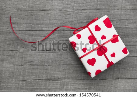 Gift boxes wrapped in heart patterned paper on a grey wooden background for birthday or valentine.