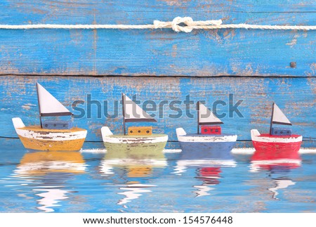Shabby toy boats in a row on blue background - on the sea - holiday, sailing, cruising concept