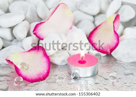 Rose petals and a lit candle for a spa decoration