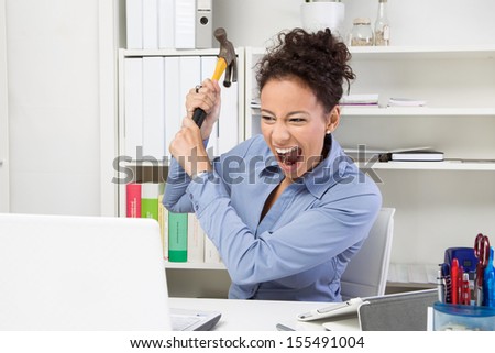 Overwhelmed woman with hammer at workplace