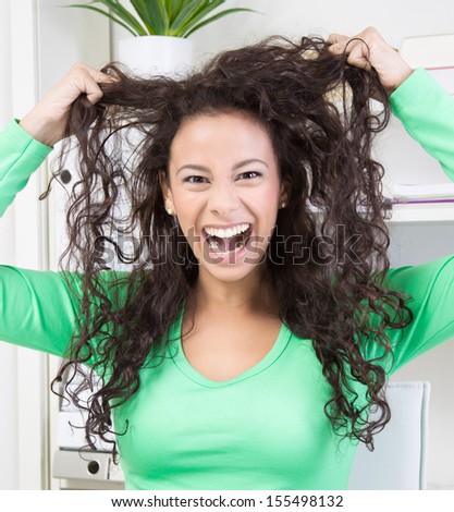 Crazy young woman making face playing with her hair.