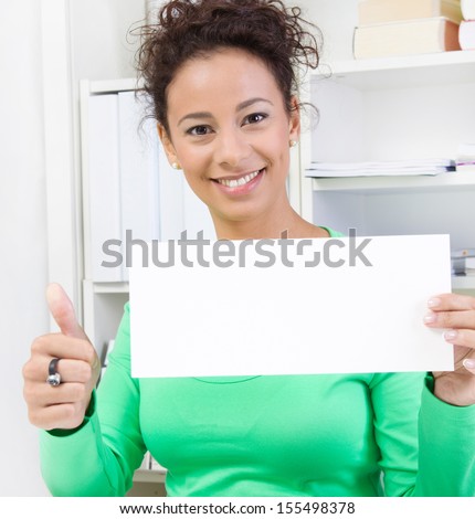 Happy young woman holding blank sign in office