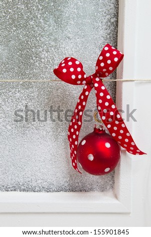 Close up of window decoration with red dotted ribbon and Christmas ball - polka dots - country style background for a greeting card